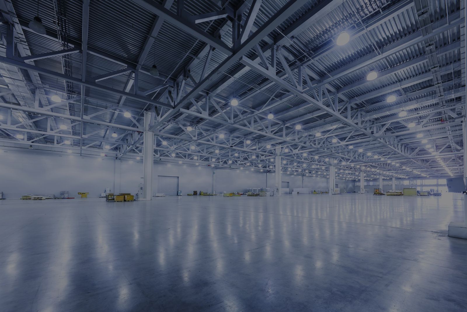 Large manufacturing floor lit by rows of LED high bay fixtures under a steel truss roof